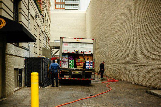Two men unloading a delivery truck in an alley